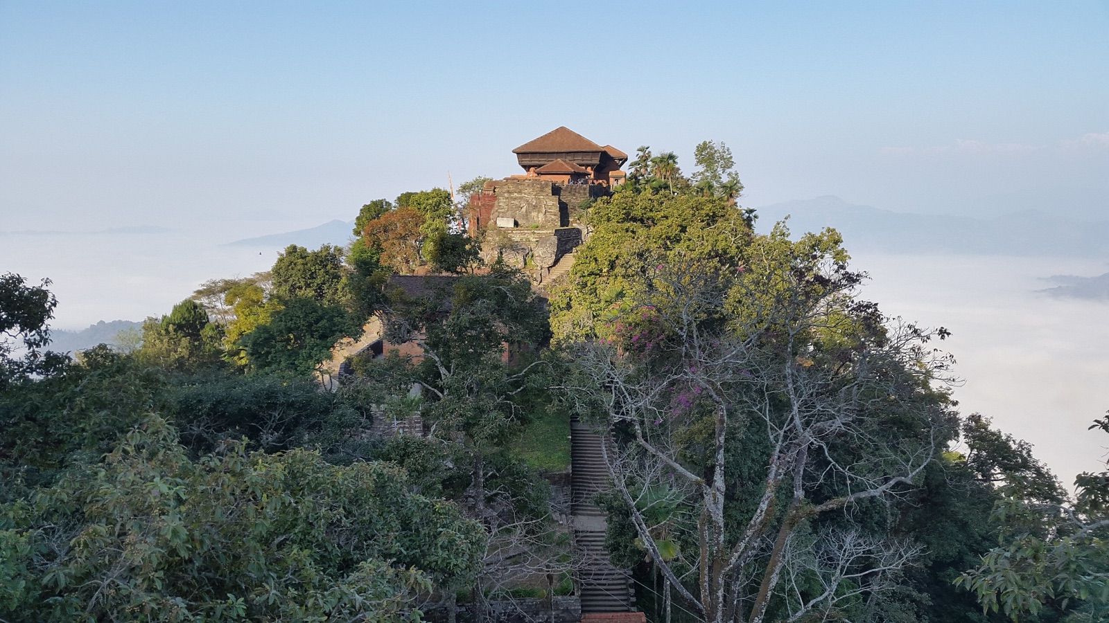 The Gorkha Durbar palace-fortress on its wooded hilltop above a sea of morning cloud, with the stone stairway climbing to it