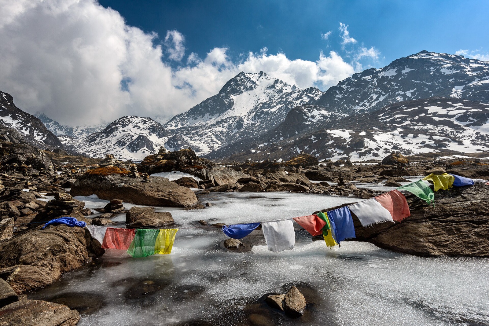 The frozen surface of sacred Gosaikunda lake at 4,380 m, strung with prayer flags below snow peaks