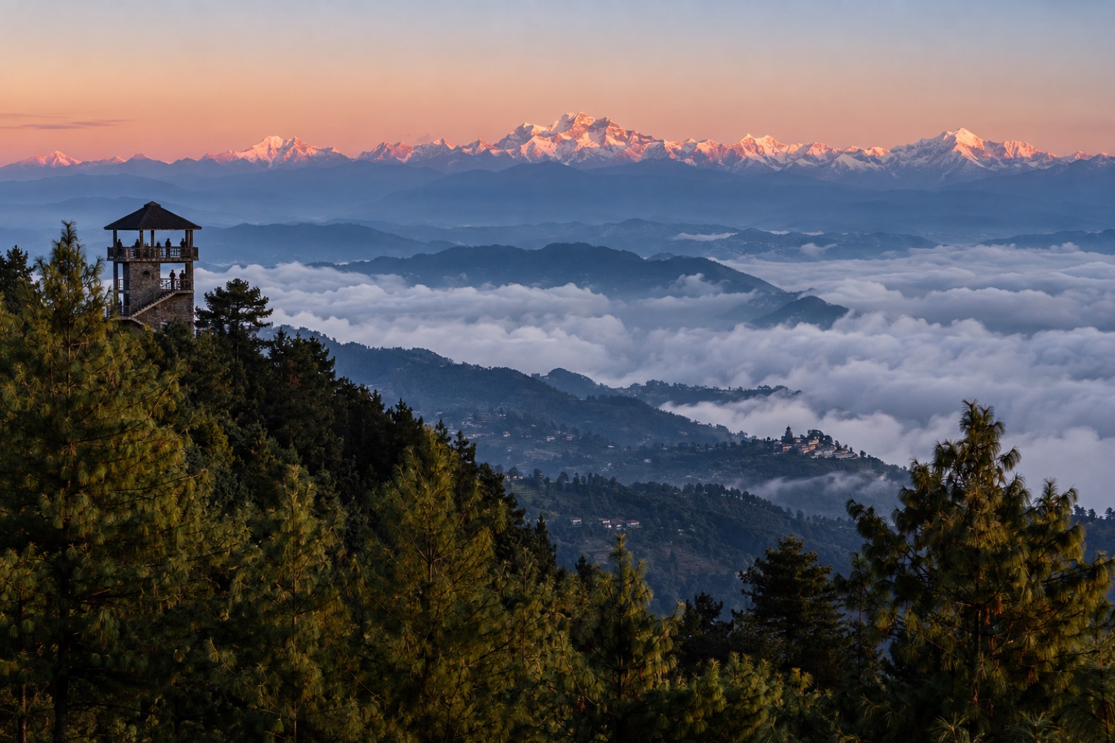 Sunrise from the Nagarkot ridge, with a view tower above a sea of cloud and the Himalaya beyond