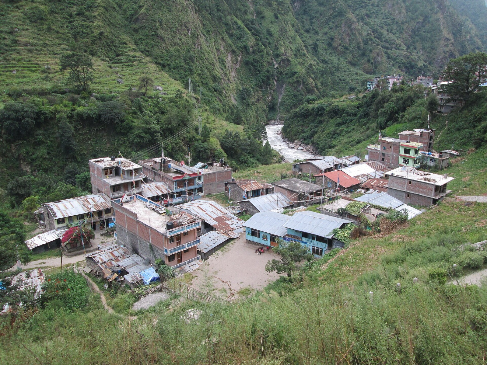 The lodges of Syabrubesi clustered above the river at the Langtang roadhead, steep forested valley walls behind